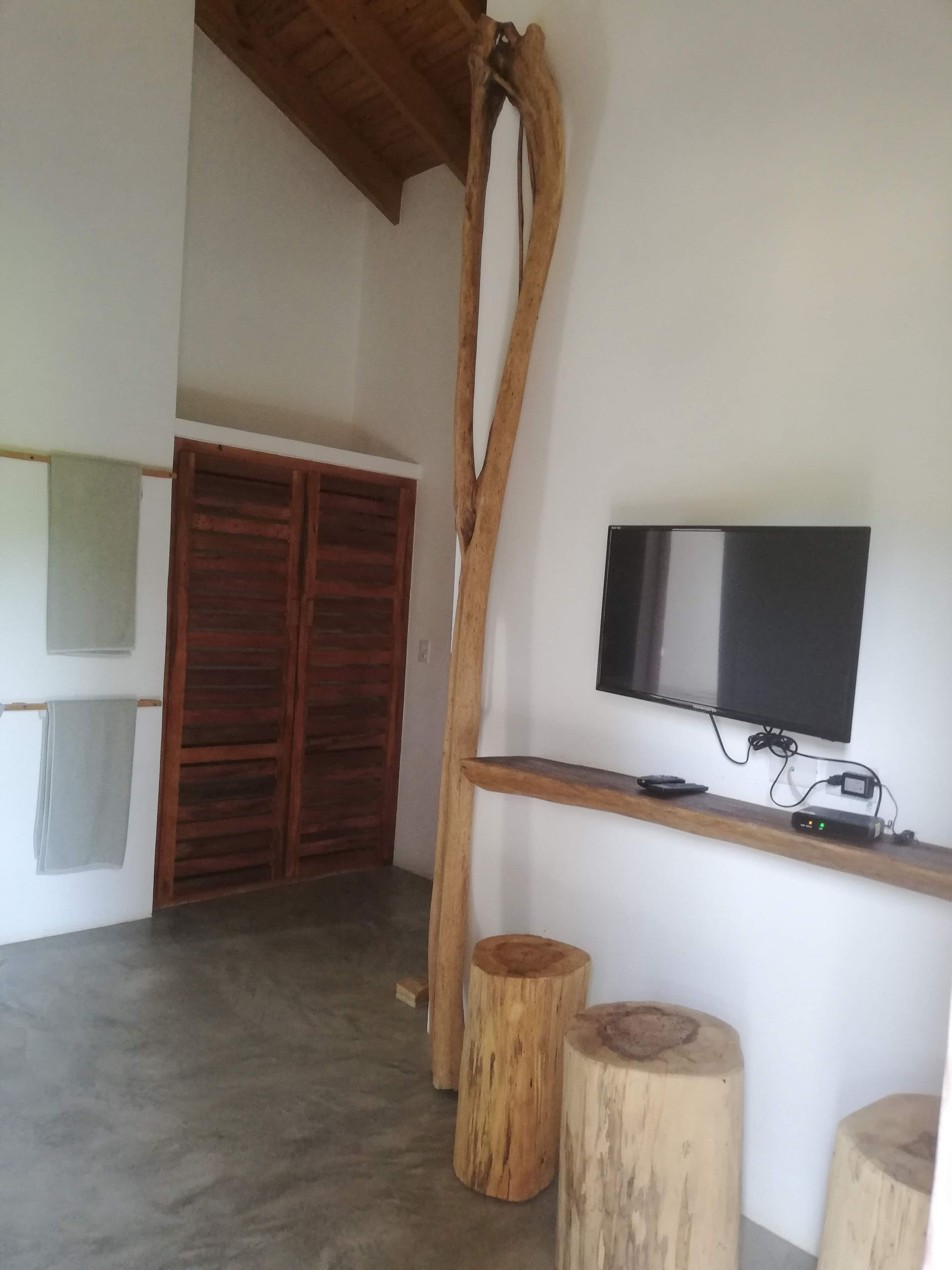 Interior with white walls, wooden accents, TV, and log stools.