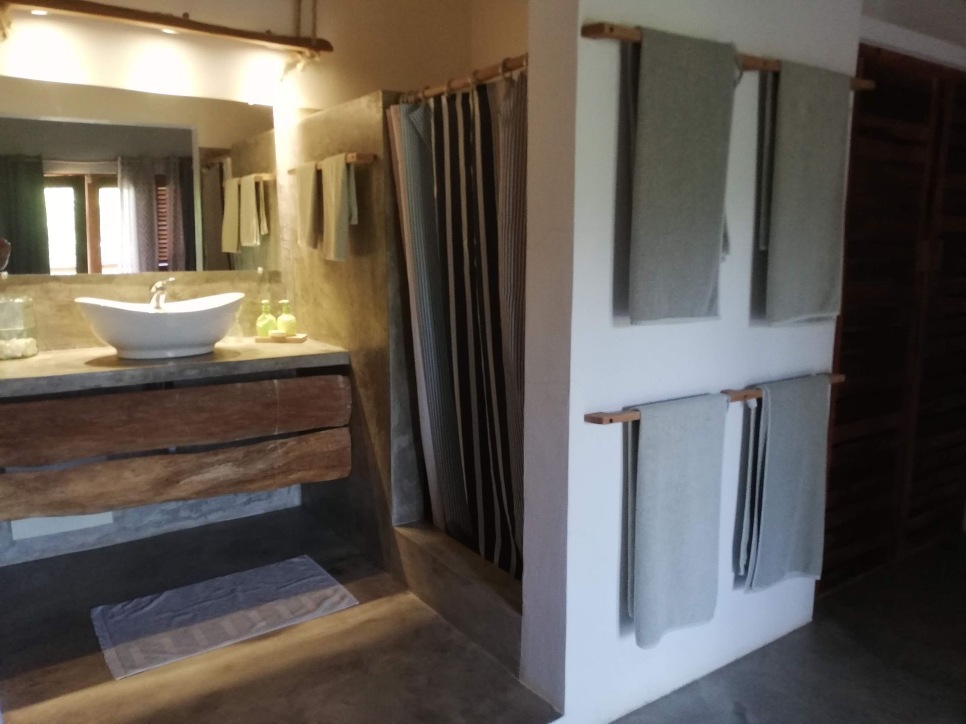 Bathroom with a rustic wooden vanity, shower curtains, and towels hanging on wooden rods.