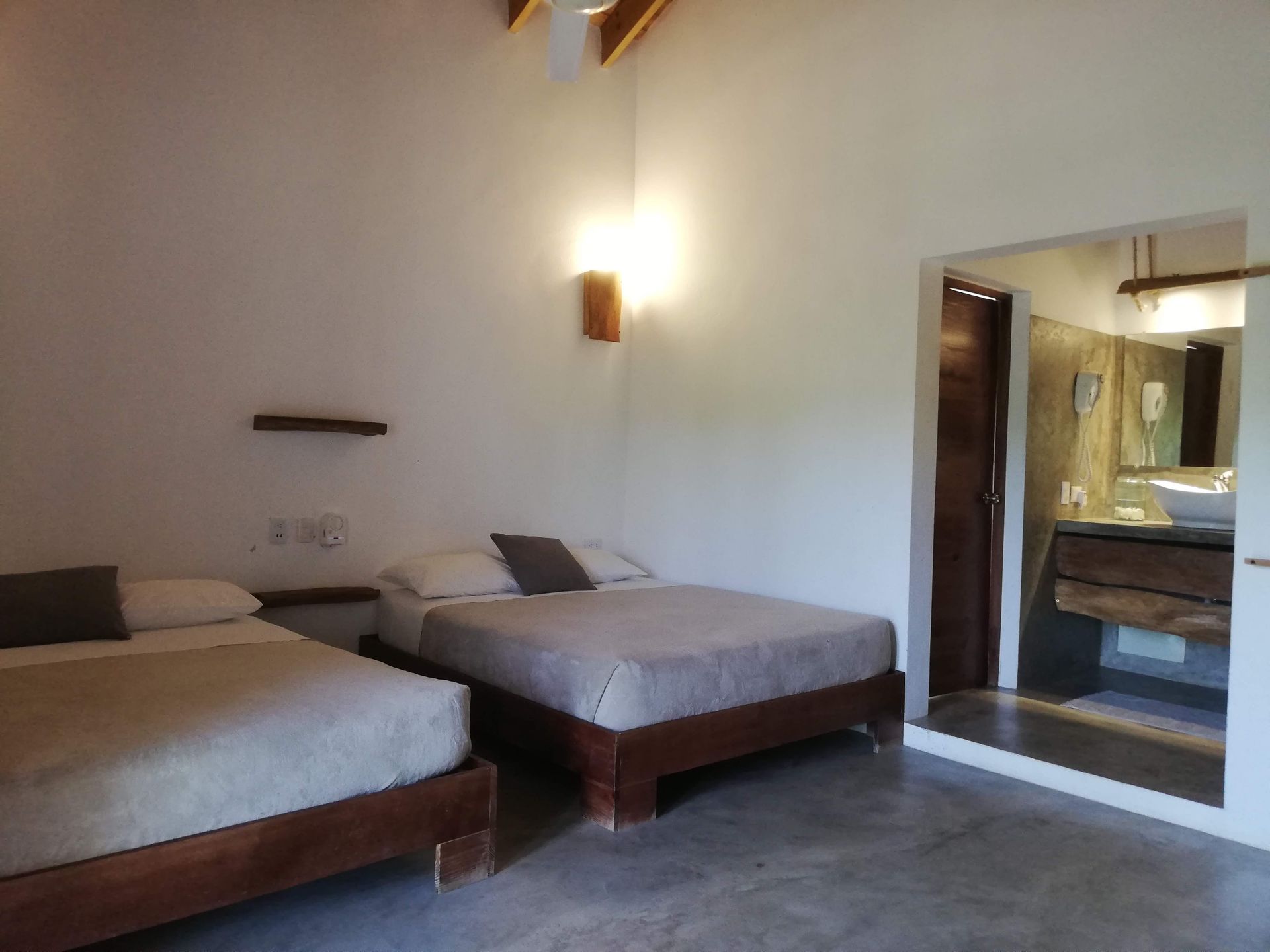 Two beds in a white-walled room with a bathroom doorway.