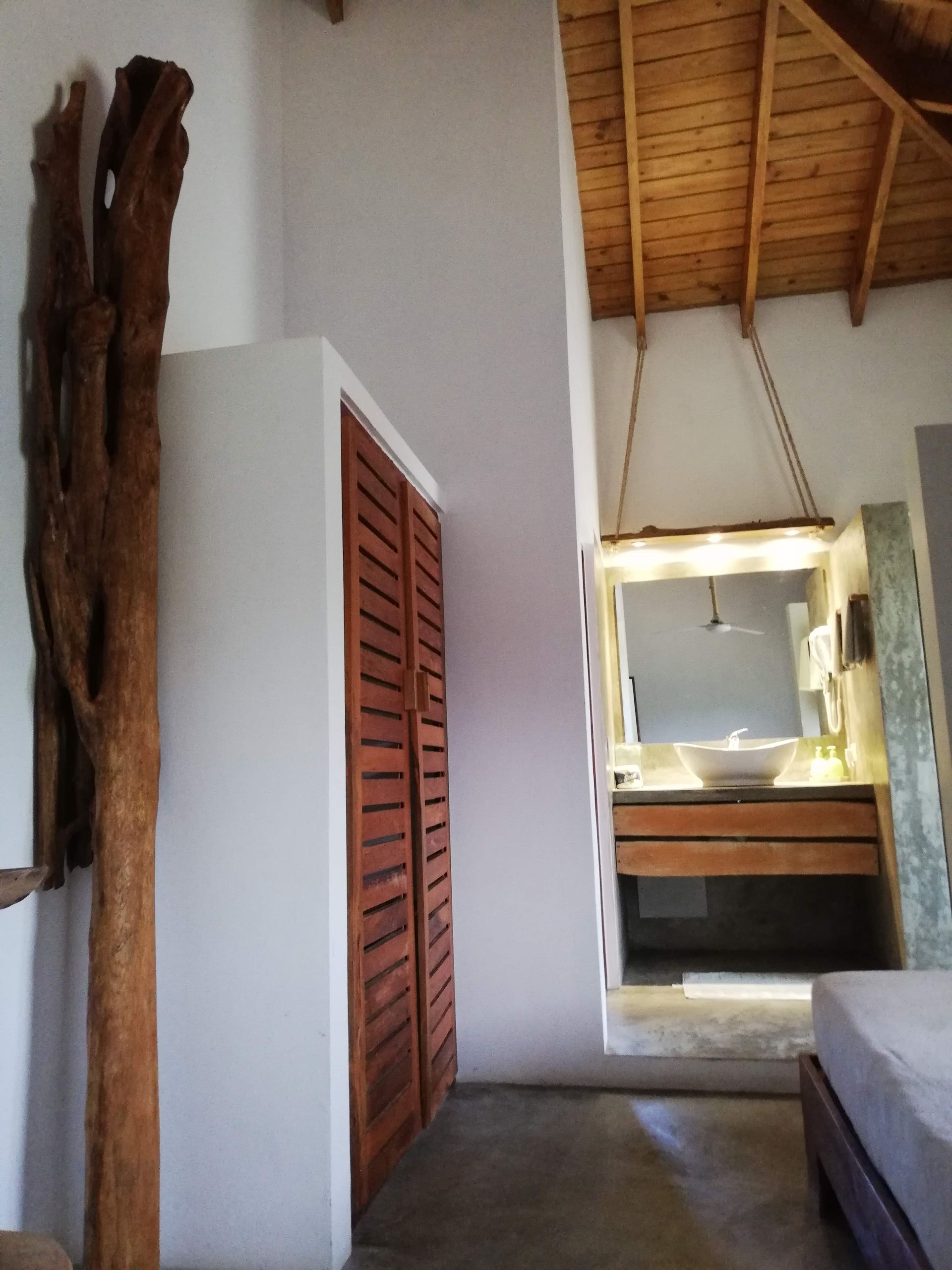 Bedroom with wooden wardrobe, natural wood sculpture, and bathroom entrance.