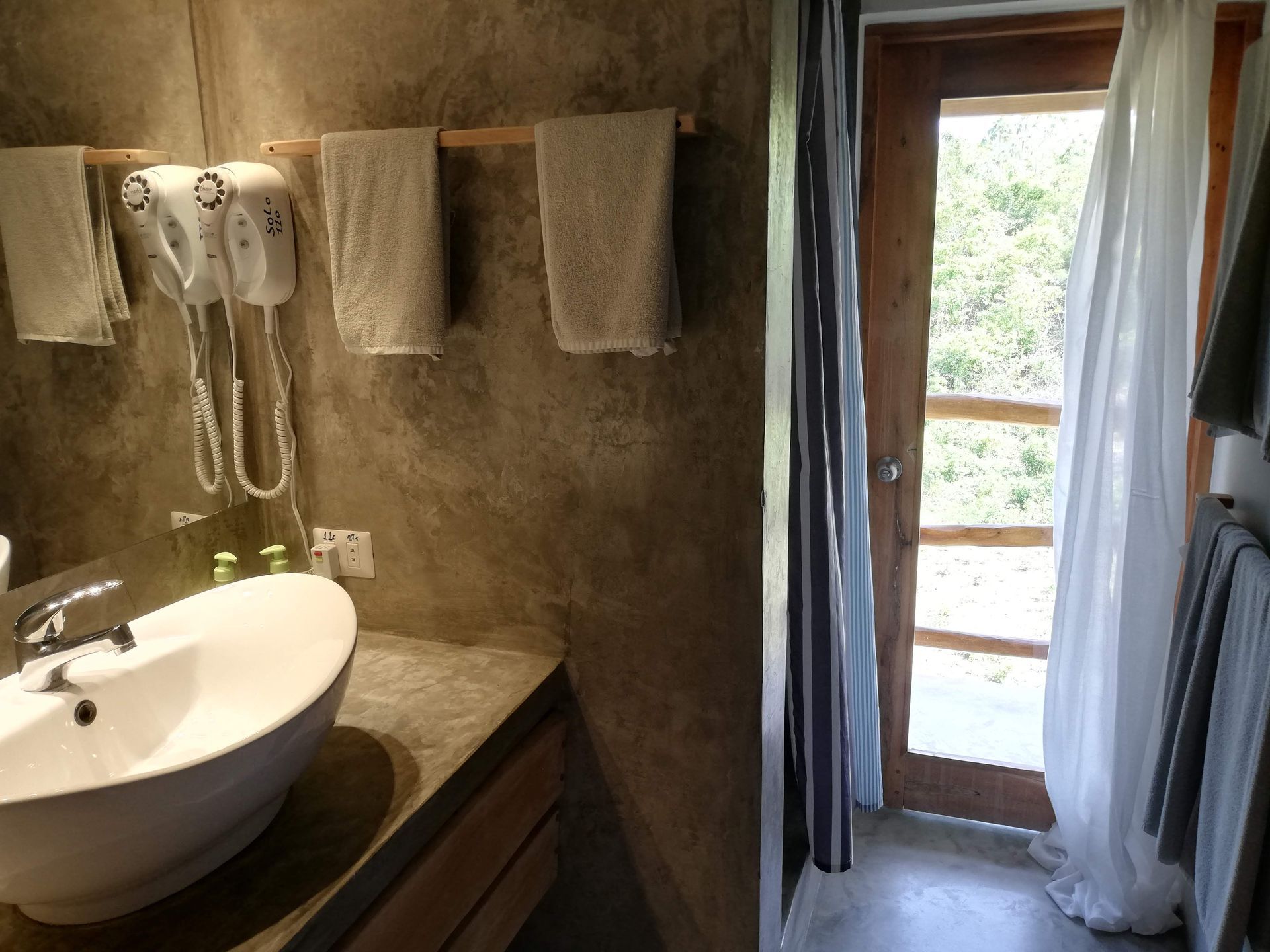 Bathroom with a white sink, towels, and a doorway with curtains.