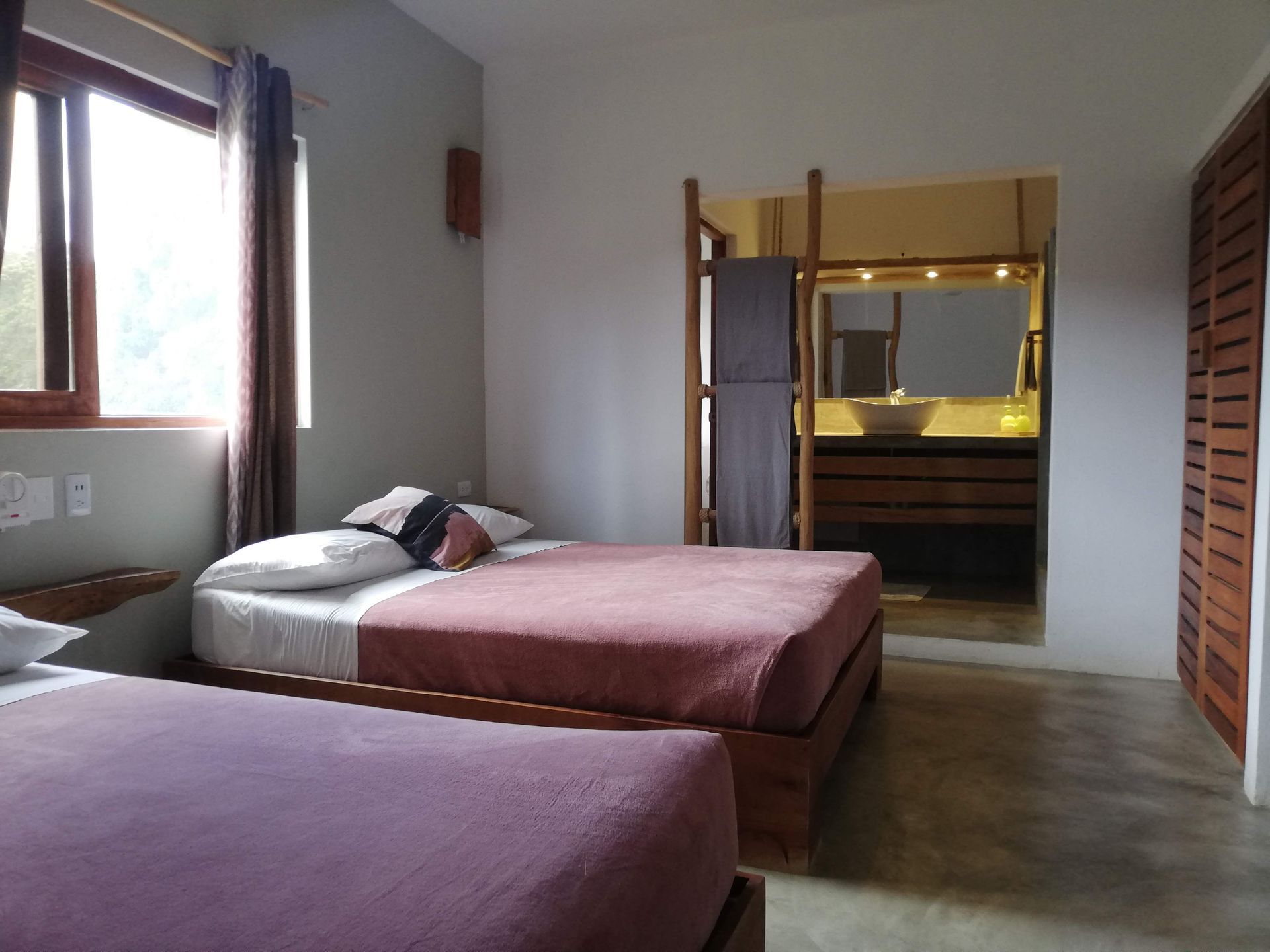 Bedroom with two beds, a bathroom entrance, and a window.