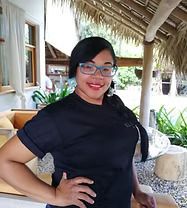 Woman wearing glasses and black shirt, smiling, outdoors.