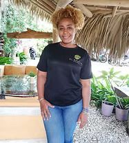 Woman with curly blonde hair in black shirt and jeans stands outside, smiling.