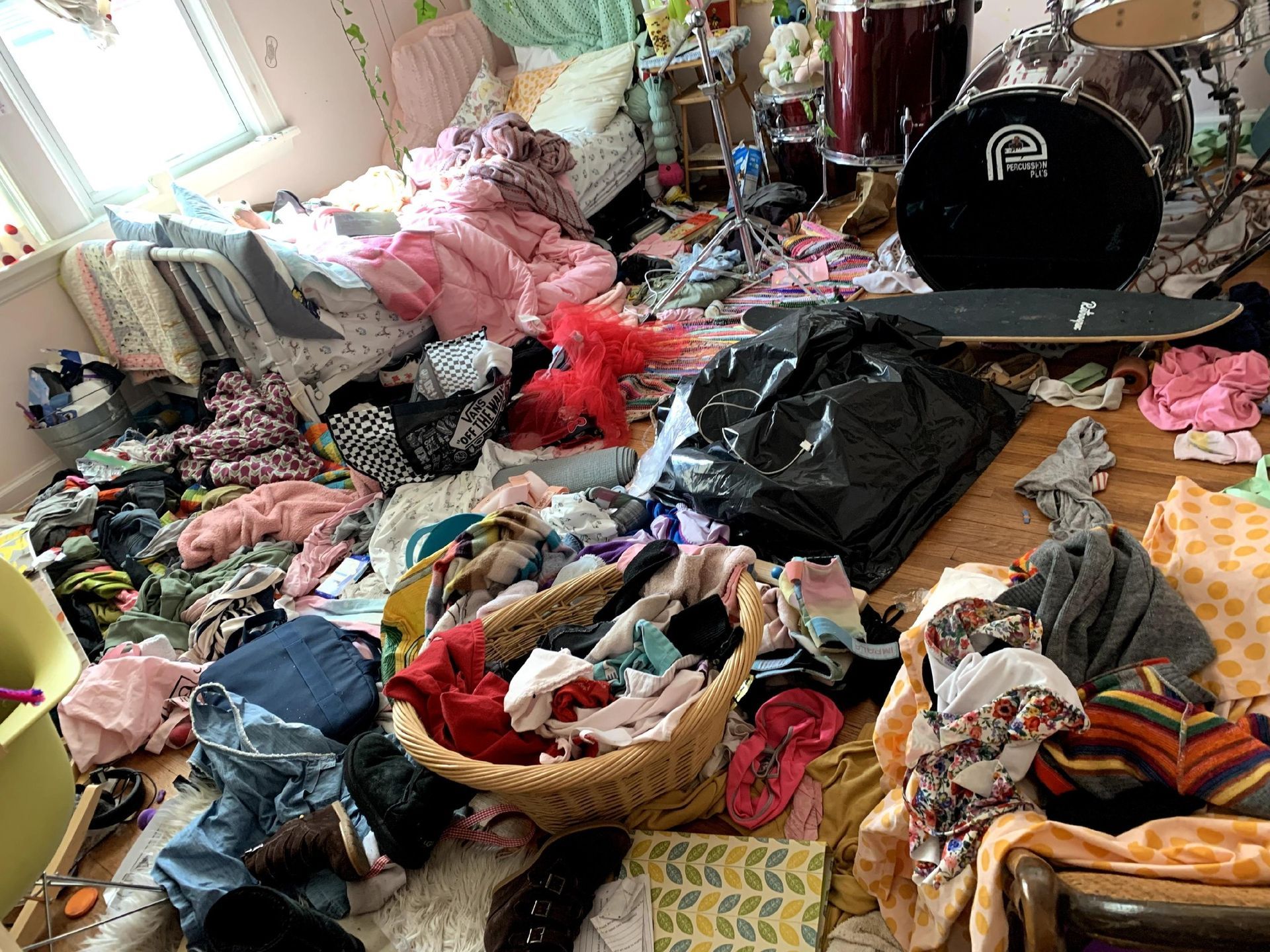 A room filled with lots of clothes and a drum set.