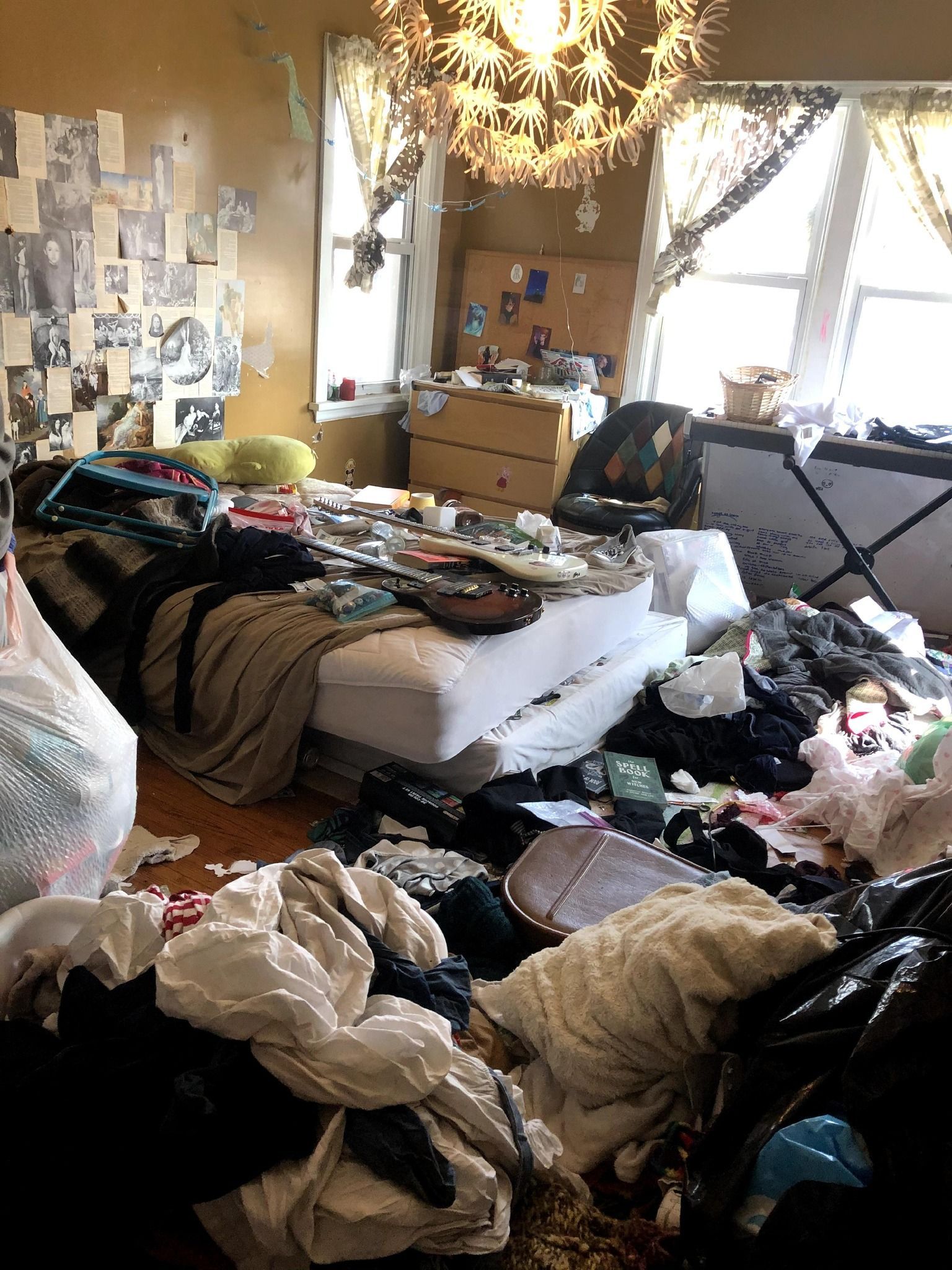 A messy bedroom with a bed , dresser , and chandelier.
