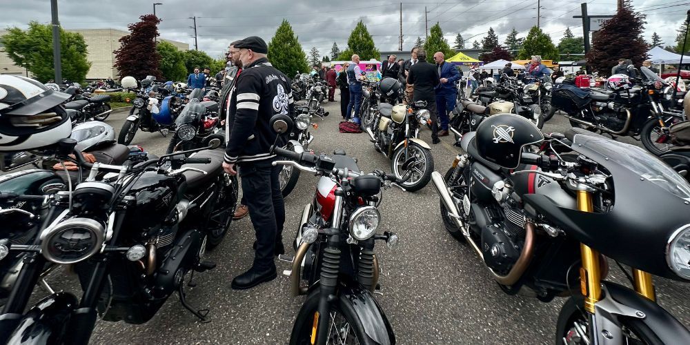 A man is standing in front of a row of motorcycles parked in a parking lot.