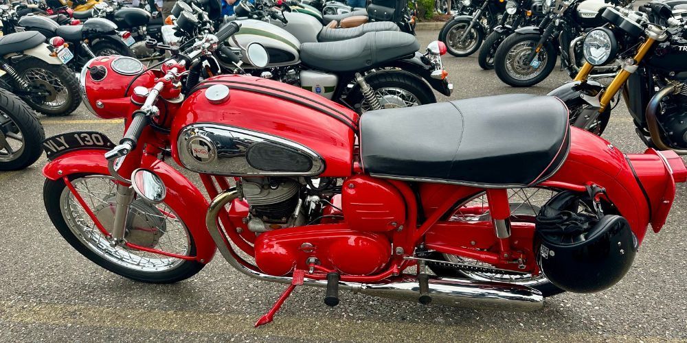 A red motorcycle is parked in a parking lot next to other motorcycles.