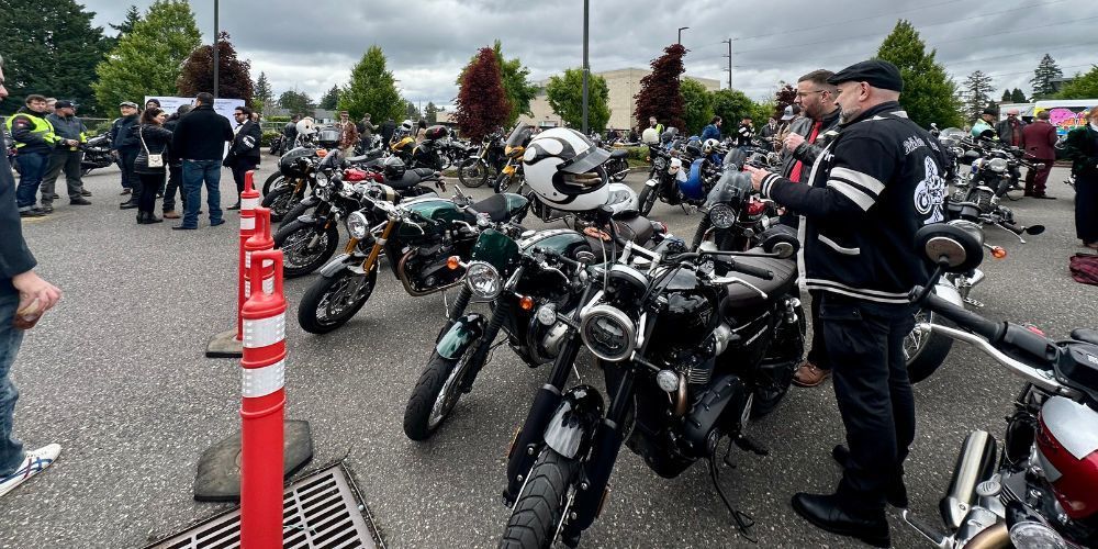 A group of people are standing around motorcycles in a parking lot.