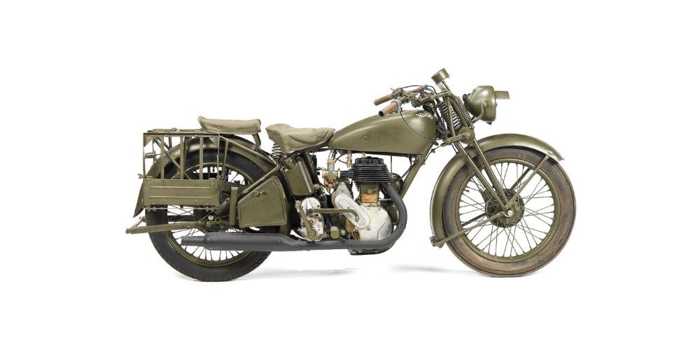 An old military motorcycle is sitting on a white surface.