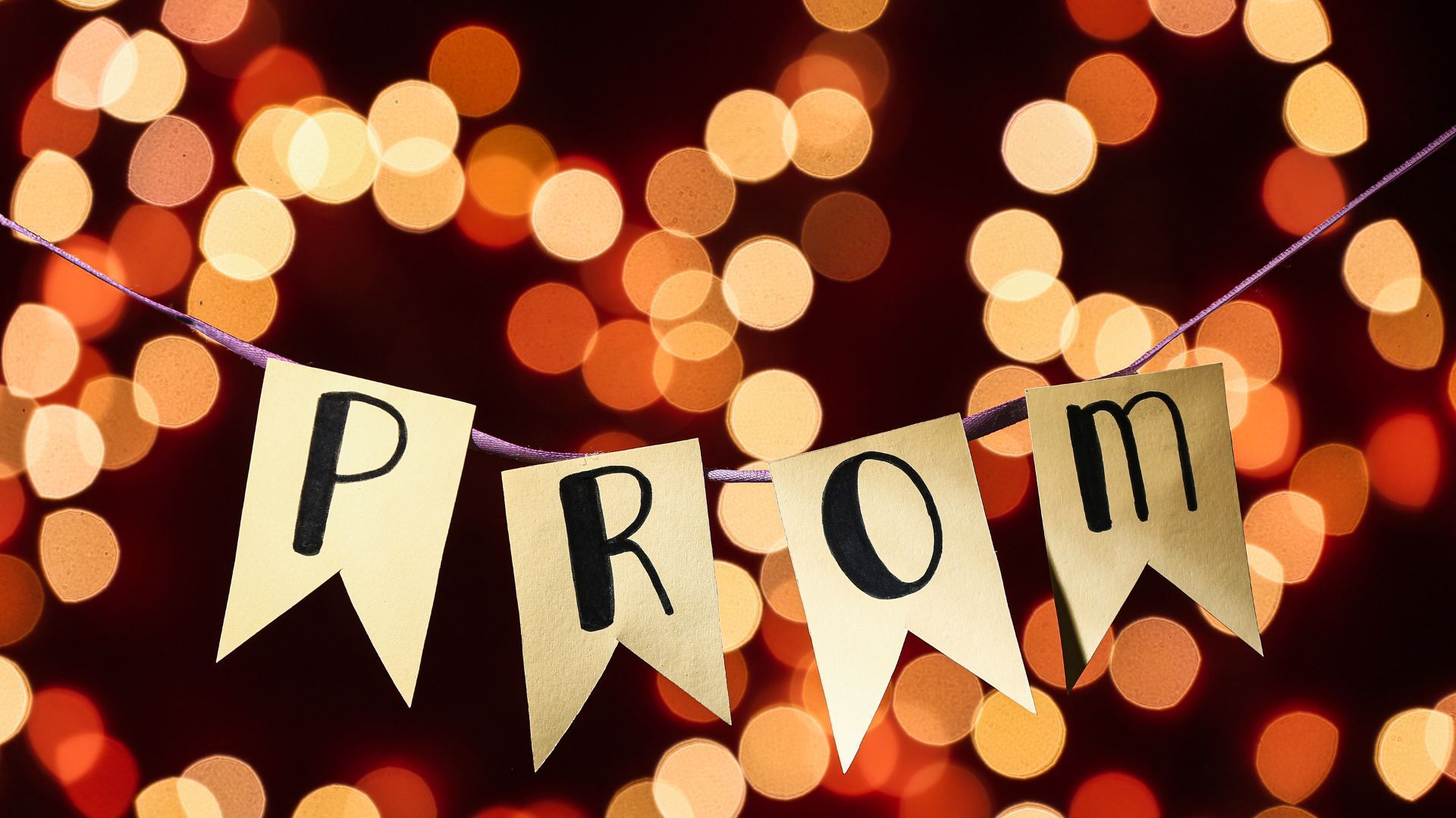 The word prom is on a banner with lights in the background