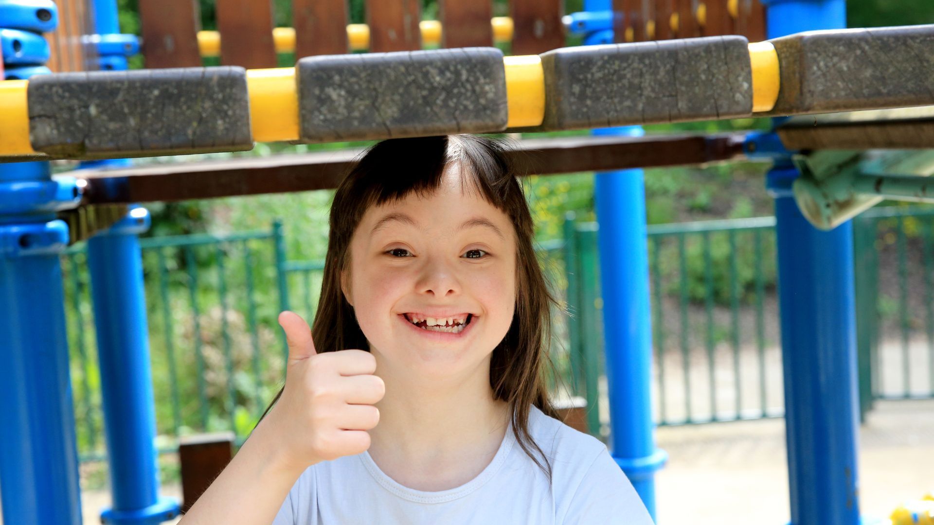 A little girl giving a thumbs up in a playground