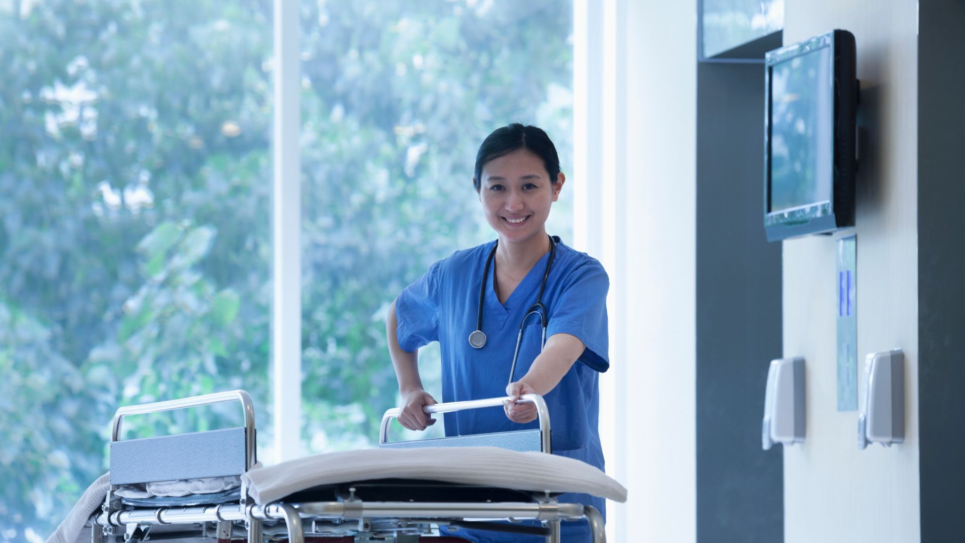 A nurse is pushing a hospital bed in a hallway