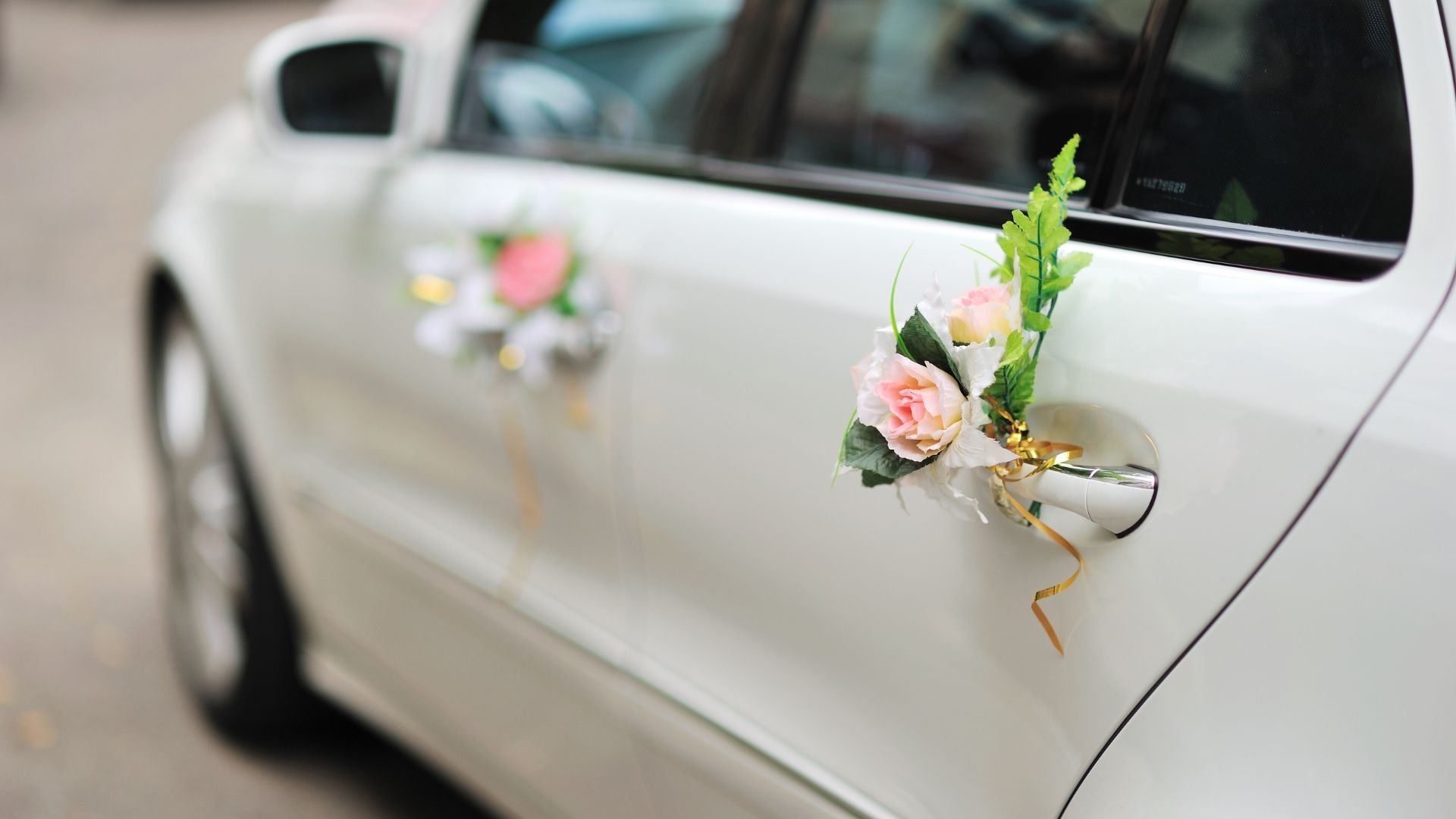 A white car with flowers on the door handles