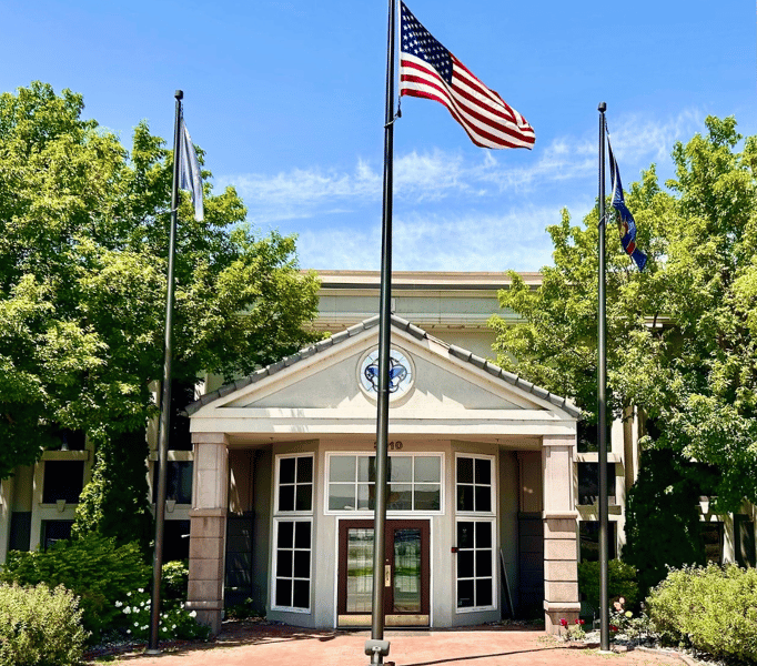 Exterior of Idaho Elite Care Medicare insurance office in Idaho Falls, featuring American flags and the main entrance for client visits