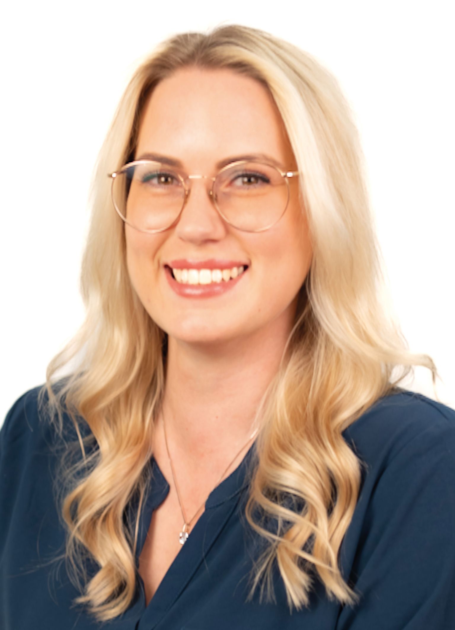 Frau mit blonden Haaren, die eine Brille trägt und in die Kamera lächelt.