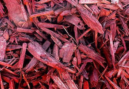 A pile of red mulch is sitting on the ground.