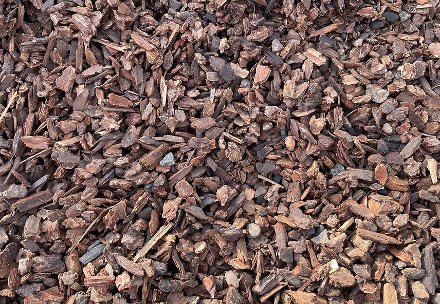 A pile of brown wood chips is sitting on the ground.