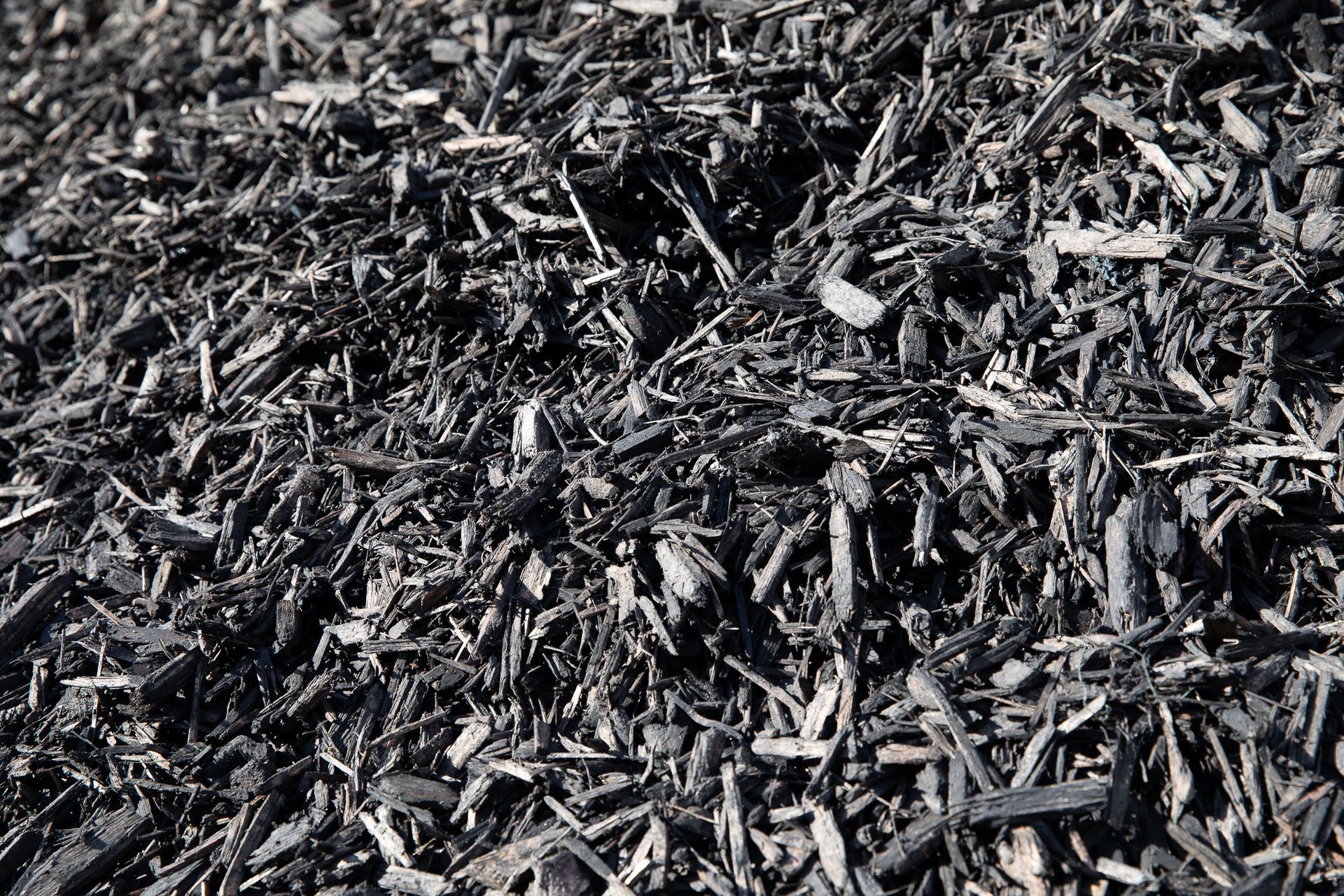 A pile of black mulch is sitting on the ground.