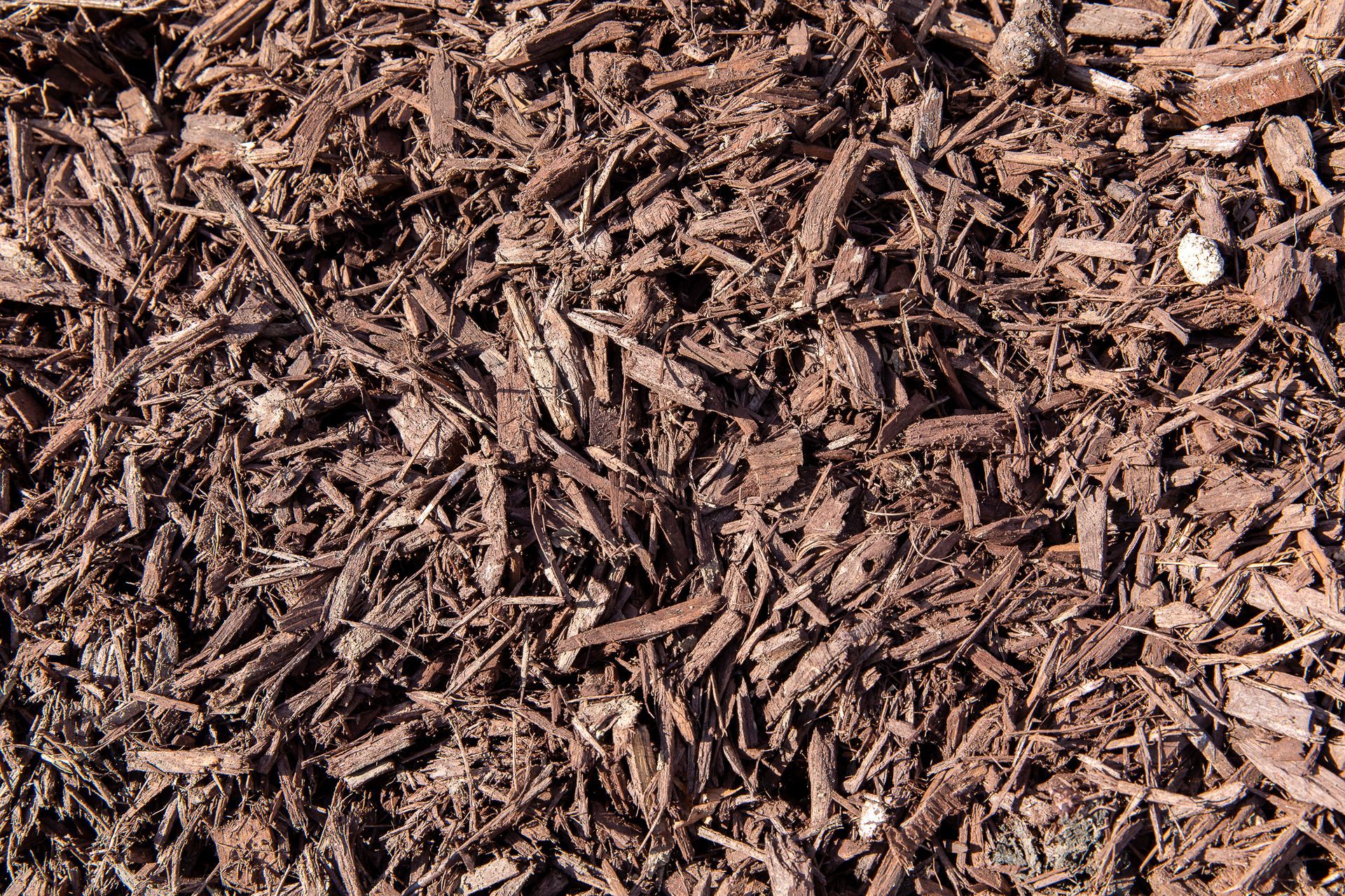 A pile of brown mulch is sitting on the ground