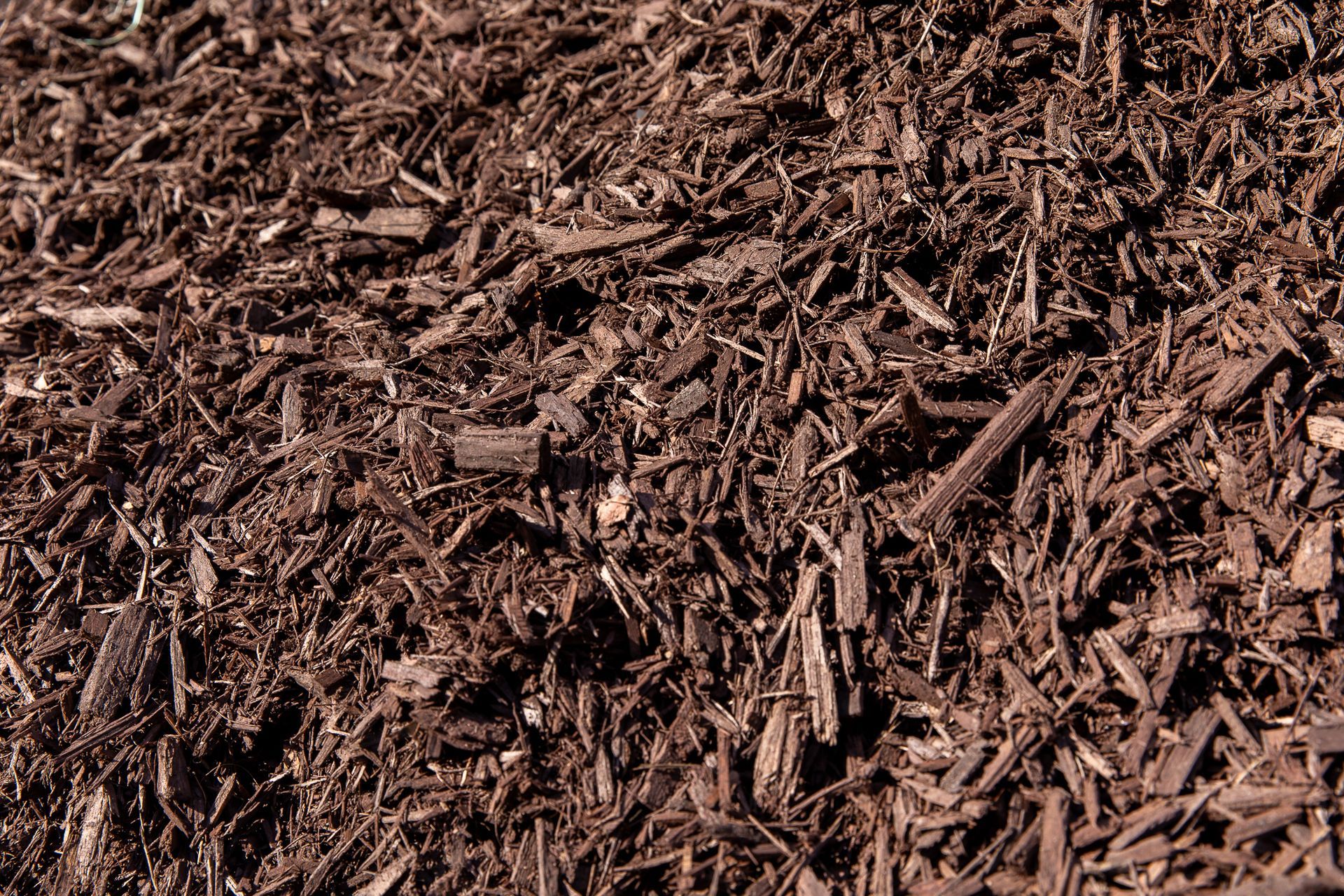 A pile of brown mulch is sitting on the ground