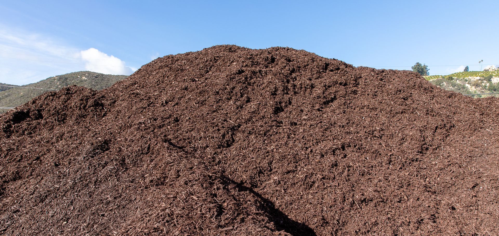 A large pile of brown gravel against a blue sky