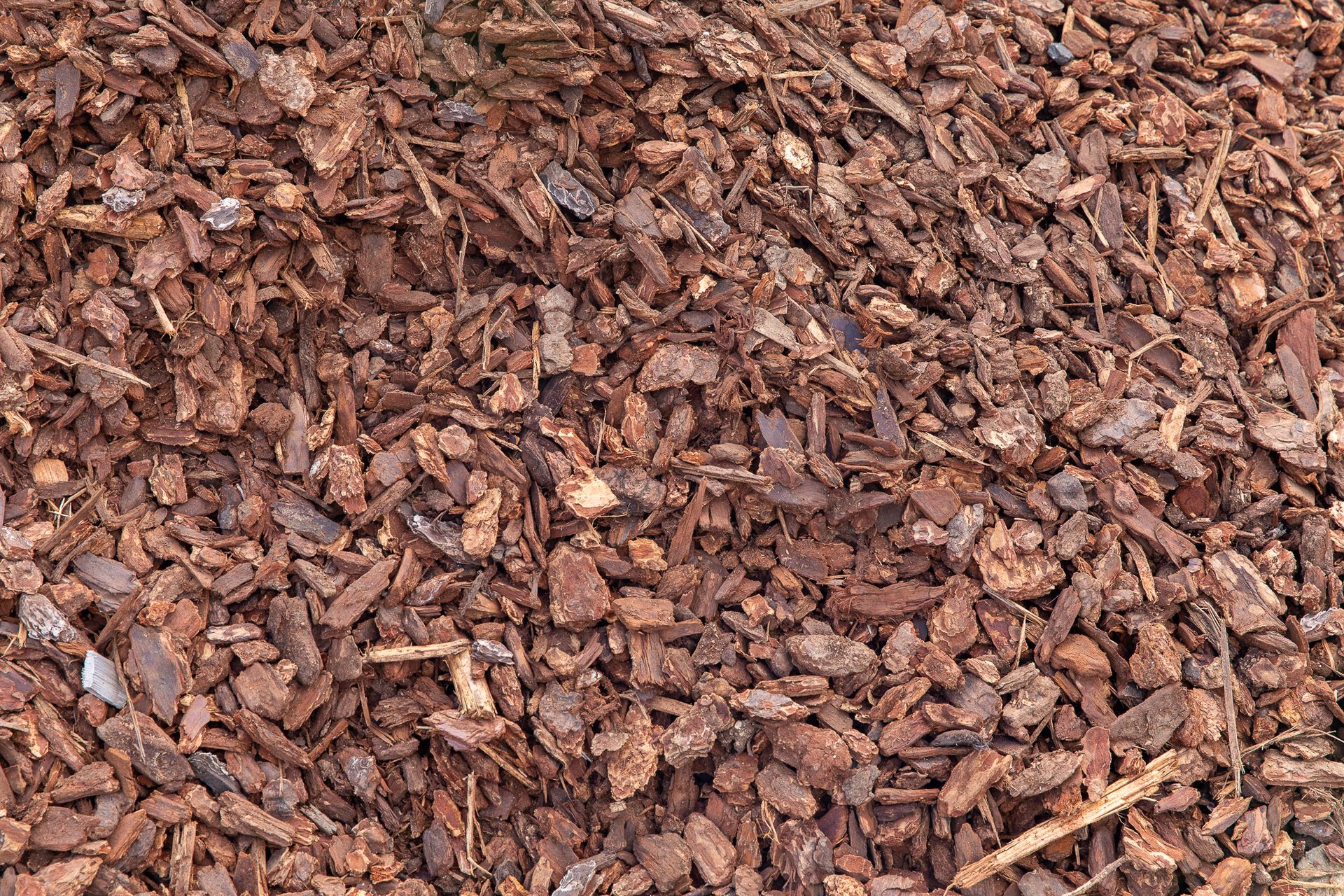A pile of brown bark is sitting on the ground.