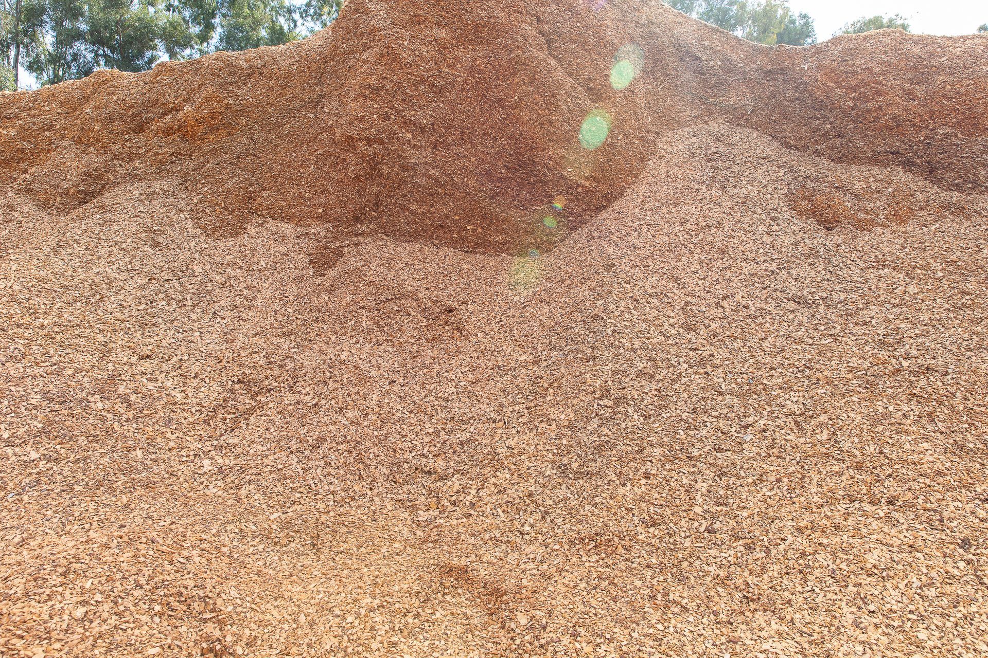 A pile of brown gravel with trees in the background