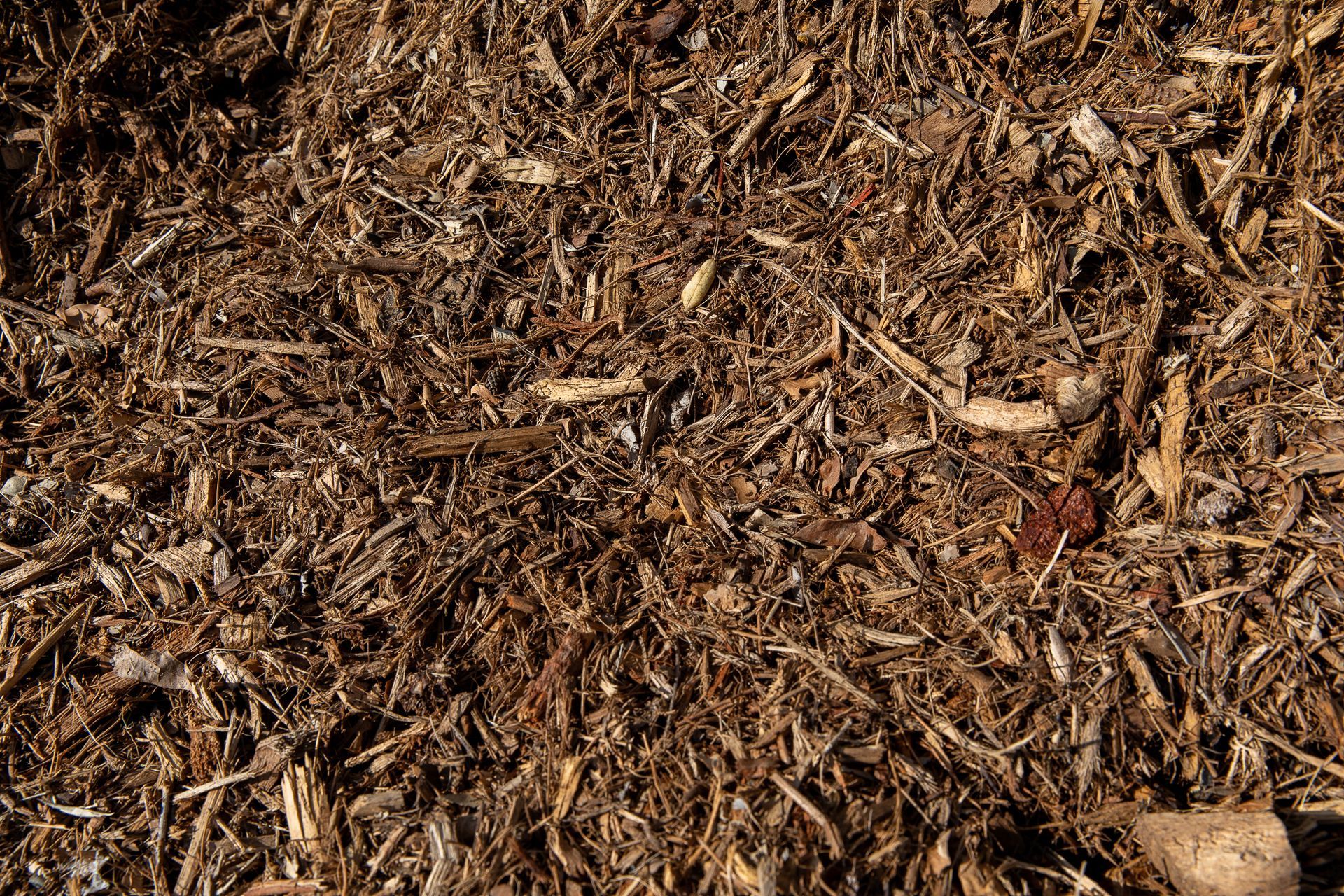 A pile of brown mulch with a few pieces of wood in it