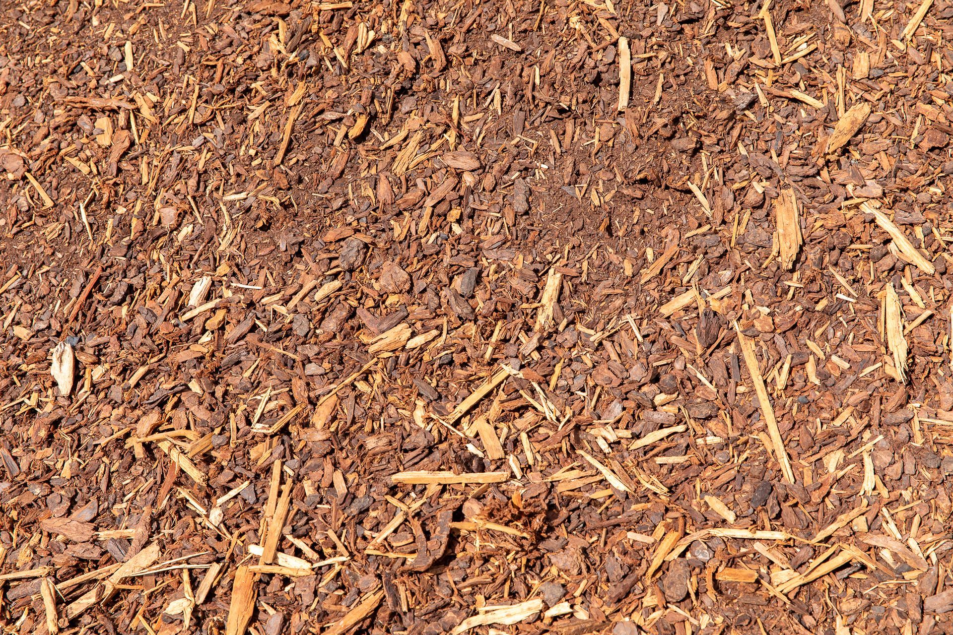 A pile of brown mulch is sitting on the ground.