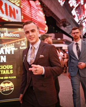 A man in a suit stands in front of a sign that says king