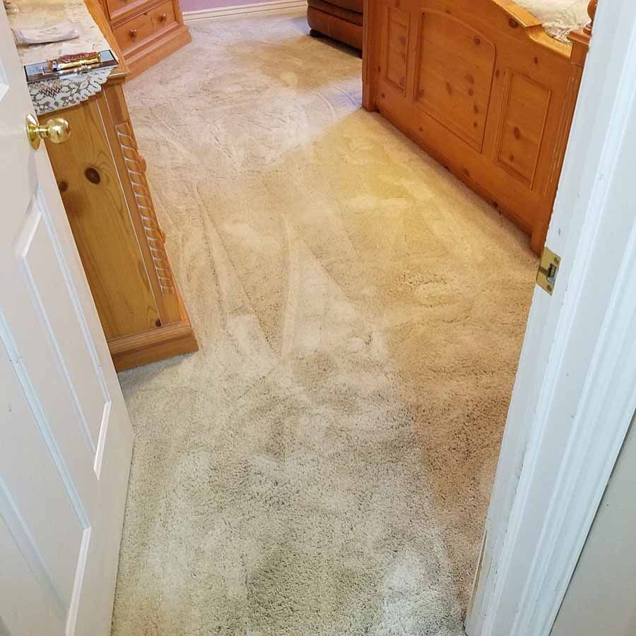 A bedroom with a carpeted floor and a wooden bed