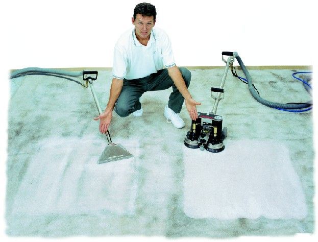 A man is cleaning a carpet with a machine
