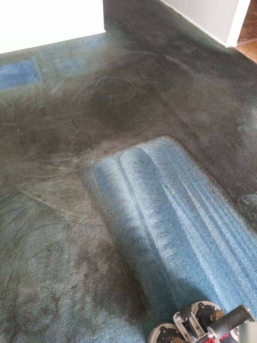 A vacuum cleaner is cleaning a dirty carpet in a living room.