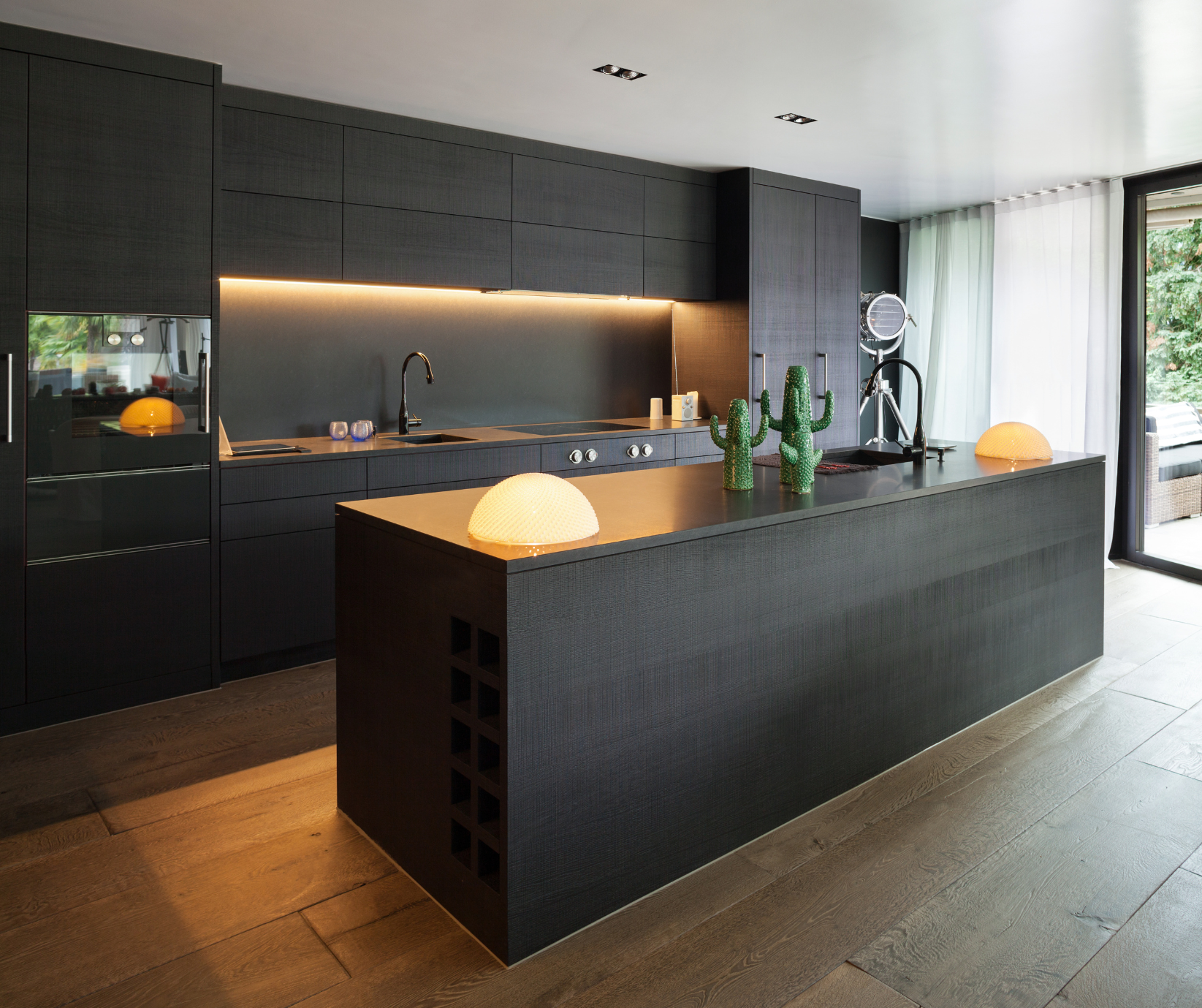 A modern Kitchen with a sleek black and gold kitchen design, fitted with golden led lighting strips.