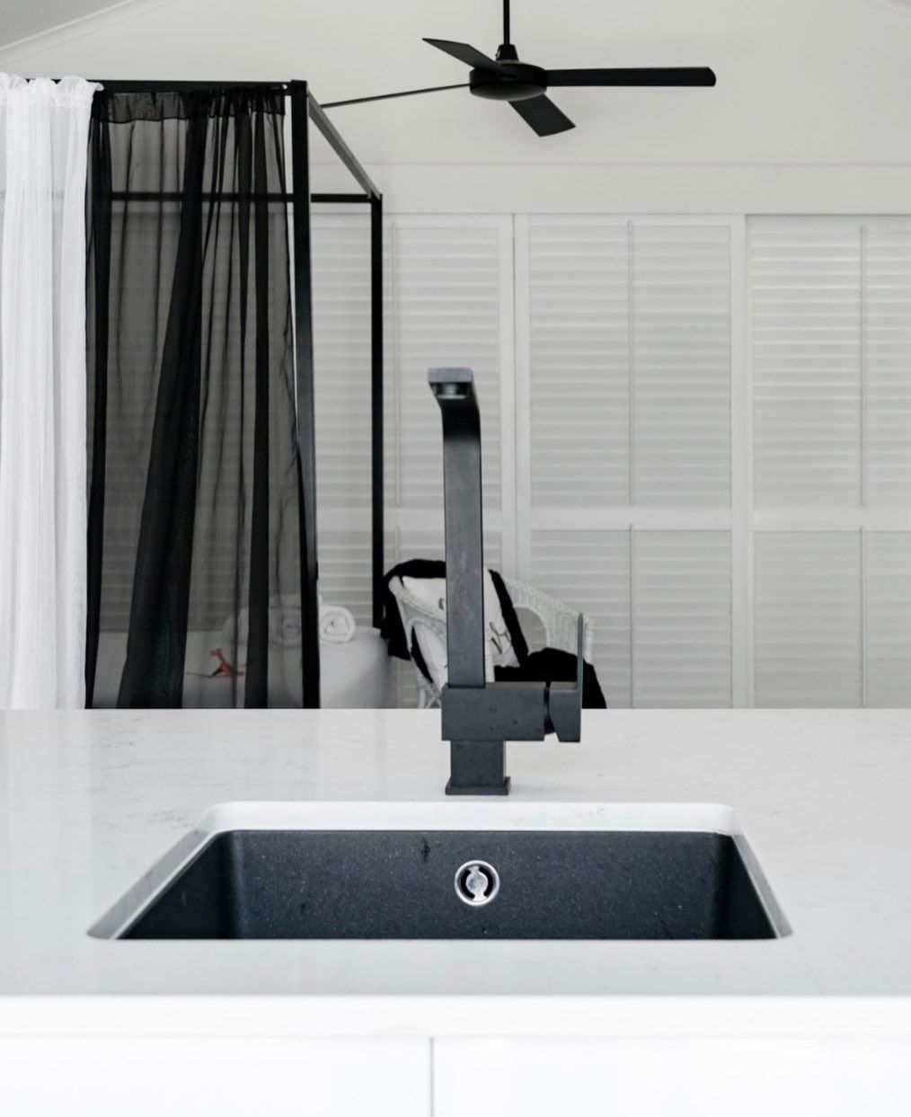 A kitchen sink with a ceiling fan in the background