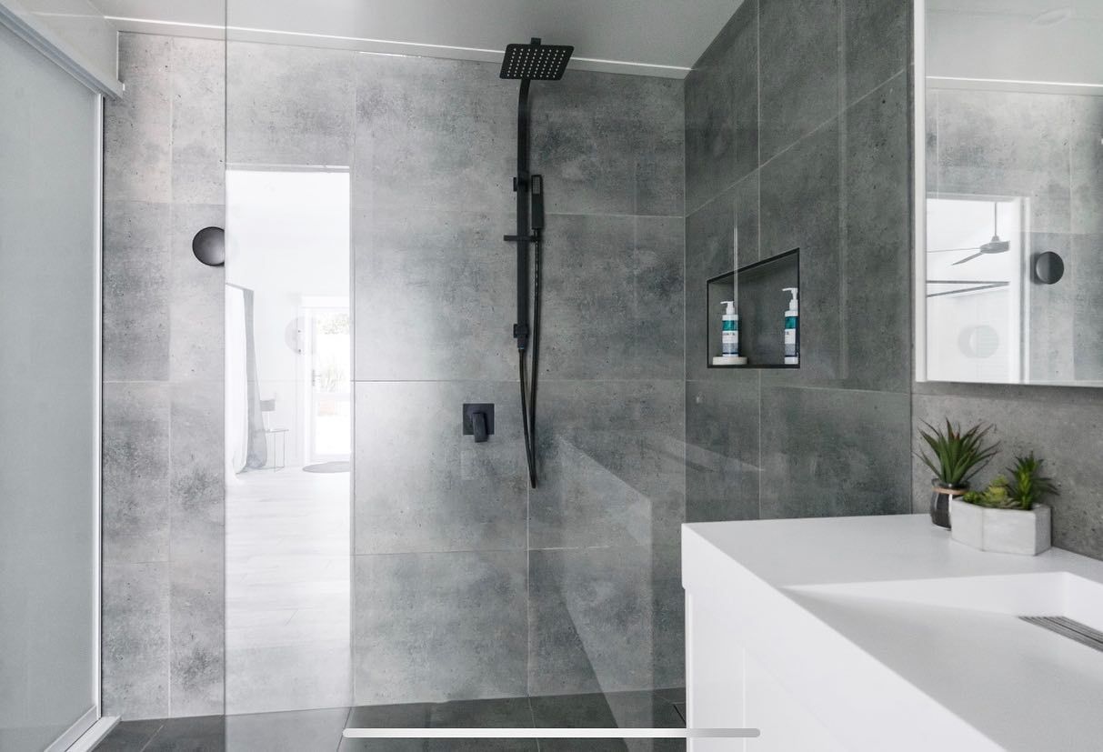 A bathroom with a walk in shower , sink and mirror.