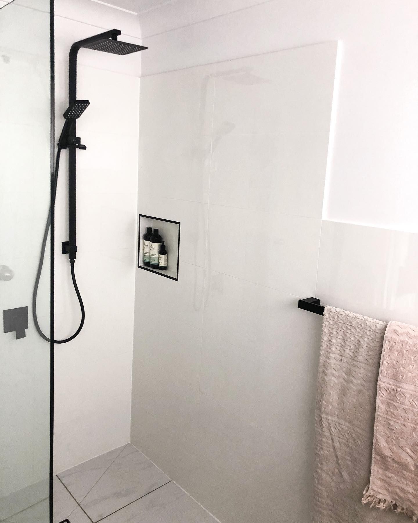 A bathroom with a shower and a towel rack.