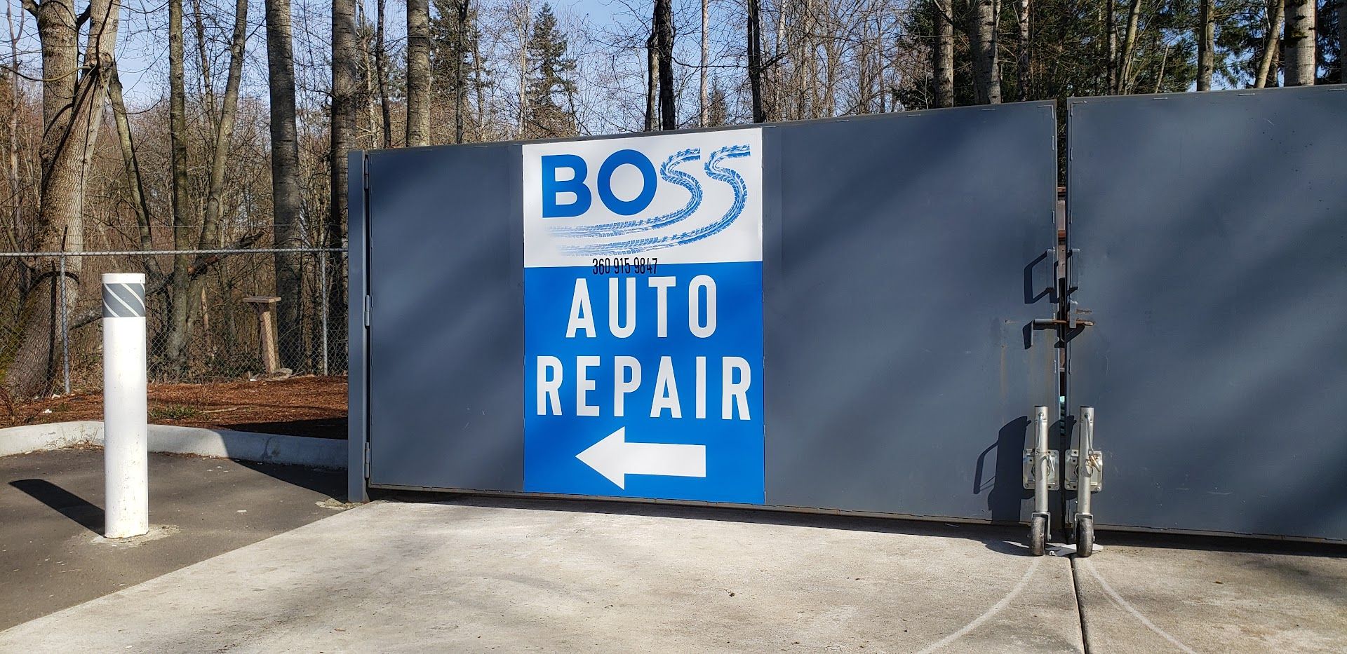 A sign for Boss Auto Repair on a blue banner on a grey gate with an arrow pointing left.| Boss Auto Repair