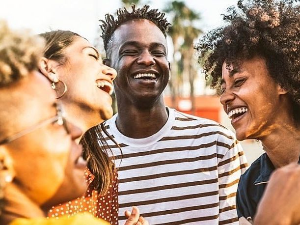 Group of friends laughing outdoors, sharing a joyful moment.