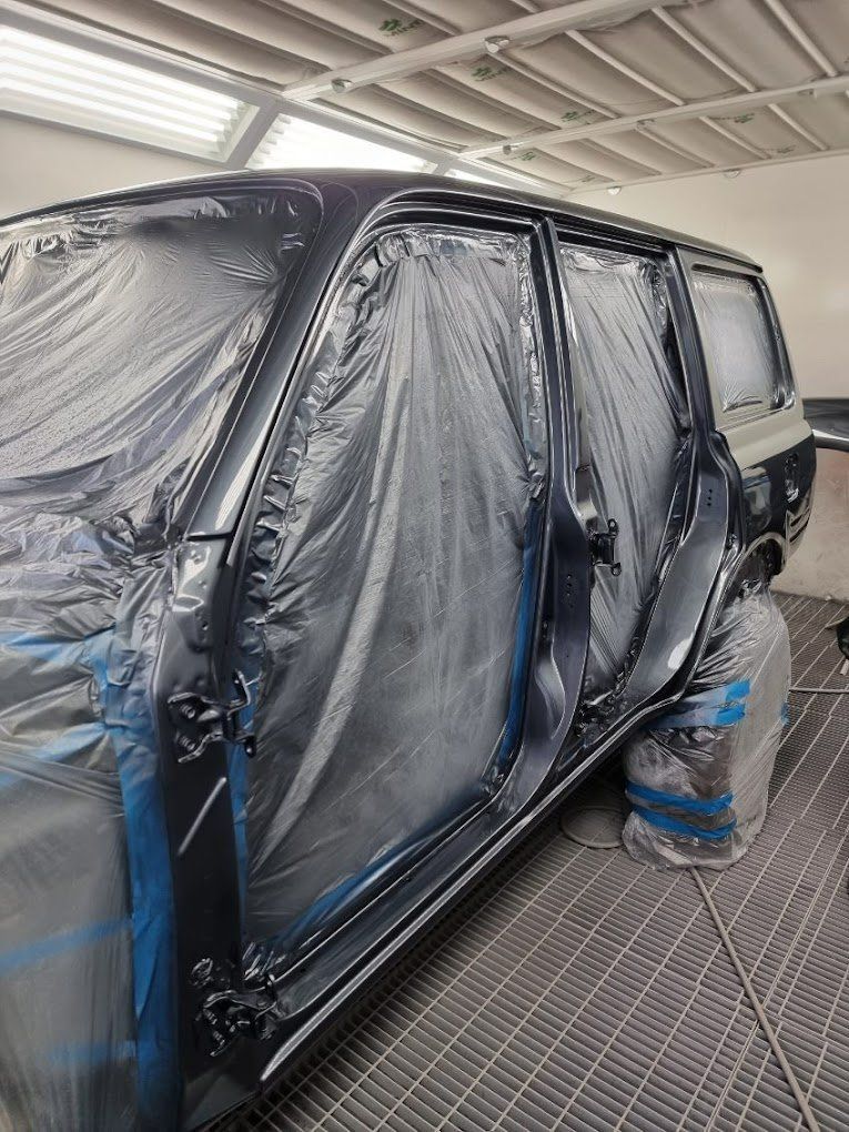 A Black Van Is Covered in Plastic in A Paint Booth — East Maitland Body Repairs in East Maitland, NSW