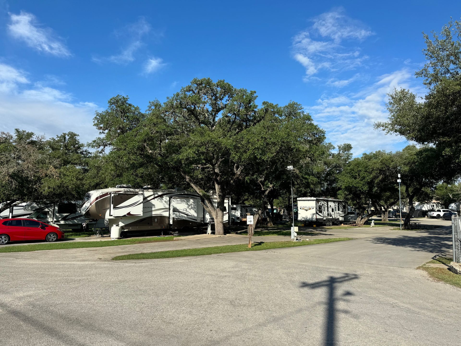 A red car is parked in a parking lot next to a rv.