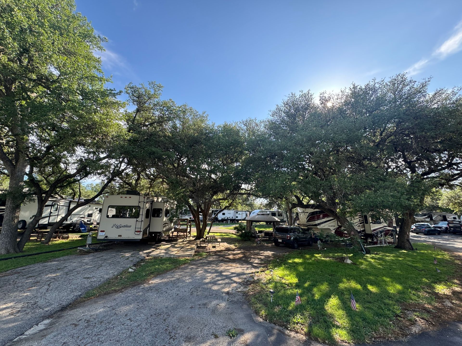 A group of rvs are parked in a lot surrounded by trees.