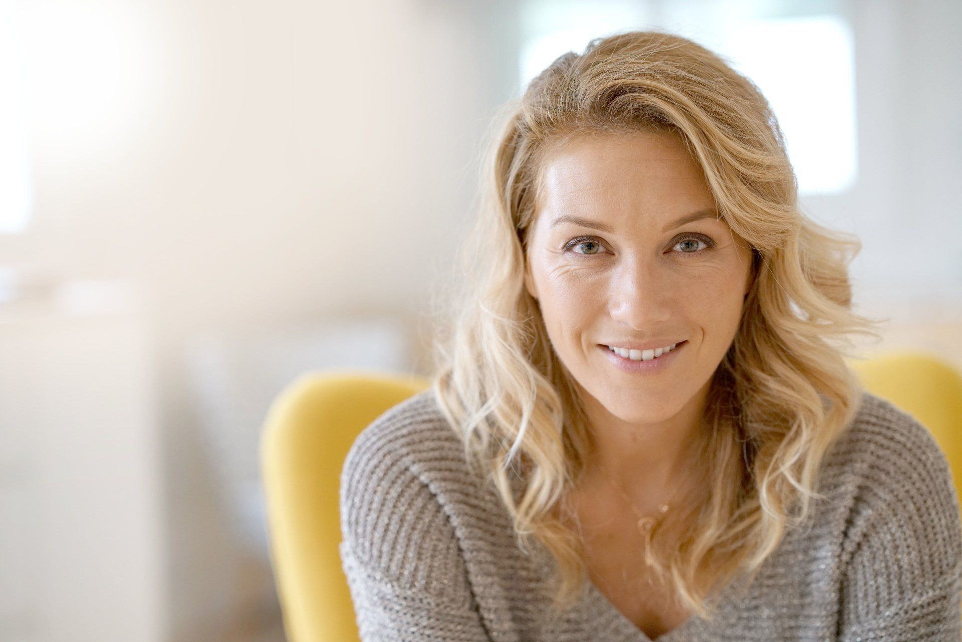 Women in yellow chair smiling at camera