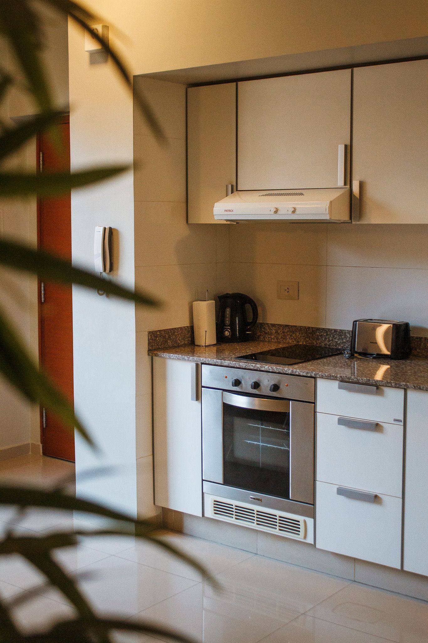 Small kitchen with white cabinets, stainless steel oven, and granite countertop.