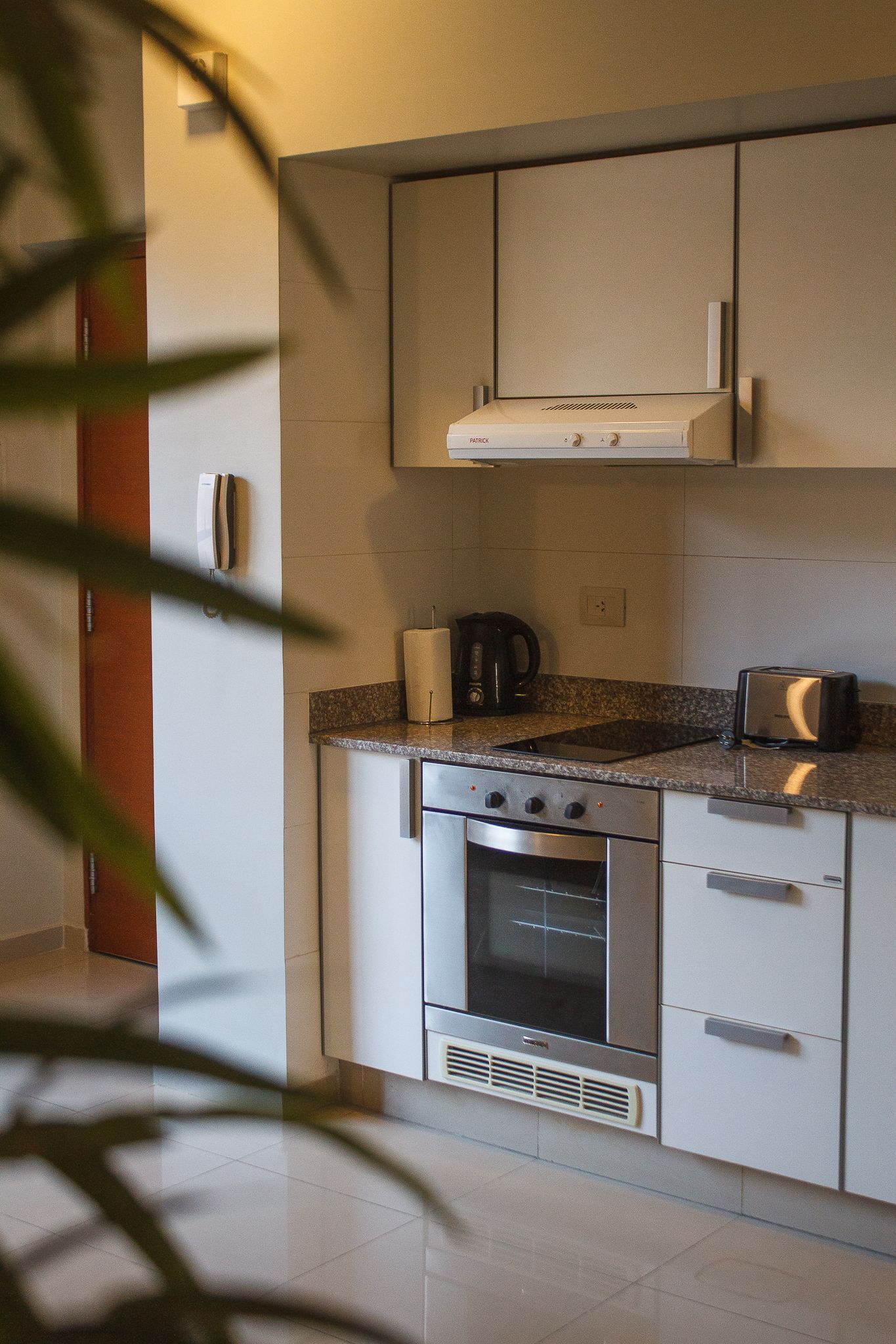 Kitchen with white cabinets, stainless steel oven, and granite countertop. A toaster and coffee maker are on the counter.