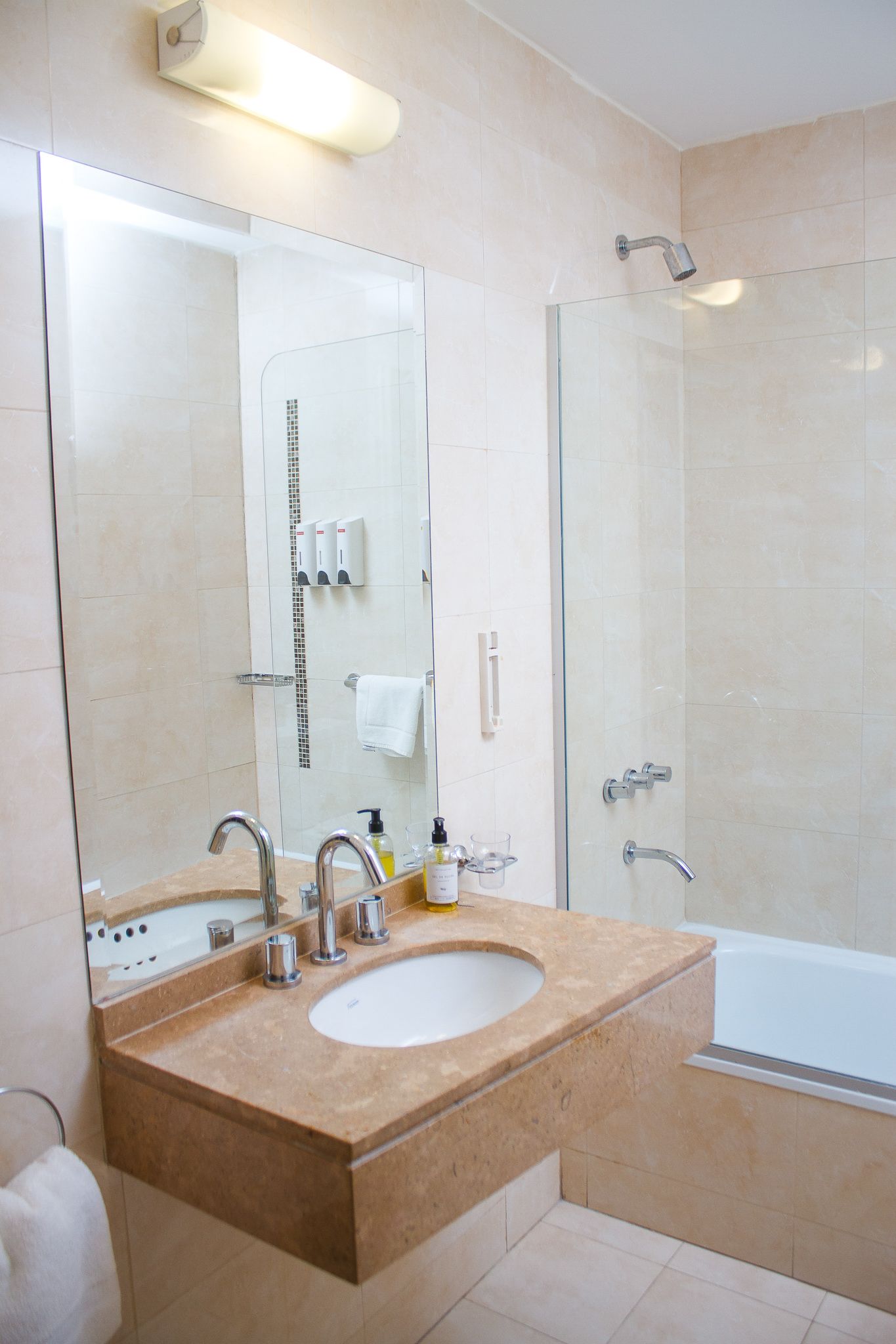 Bathroom with a beige marble vanity, sink, mirror, shower, and tub.