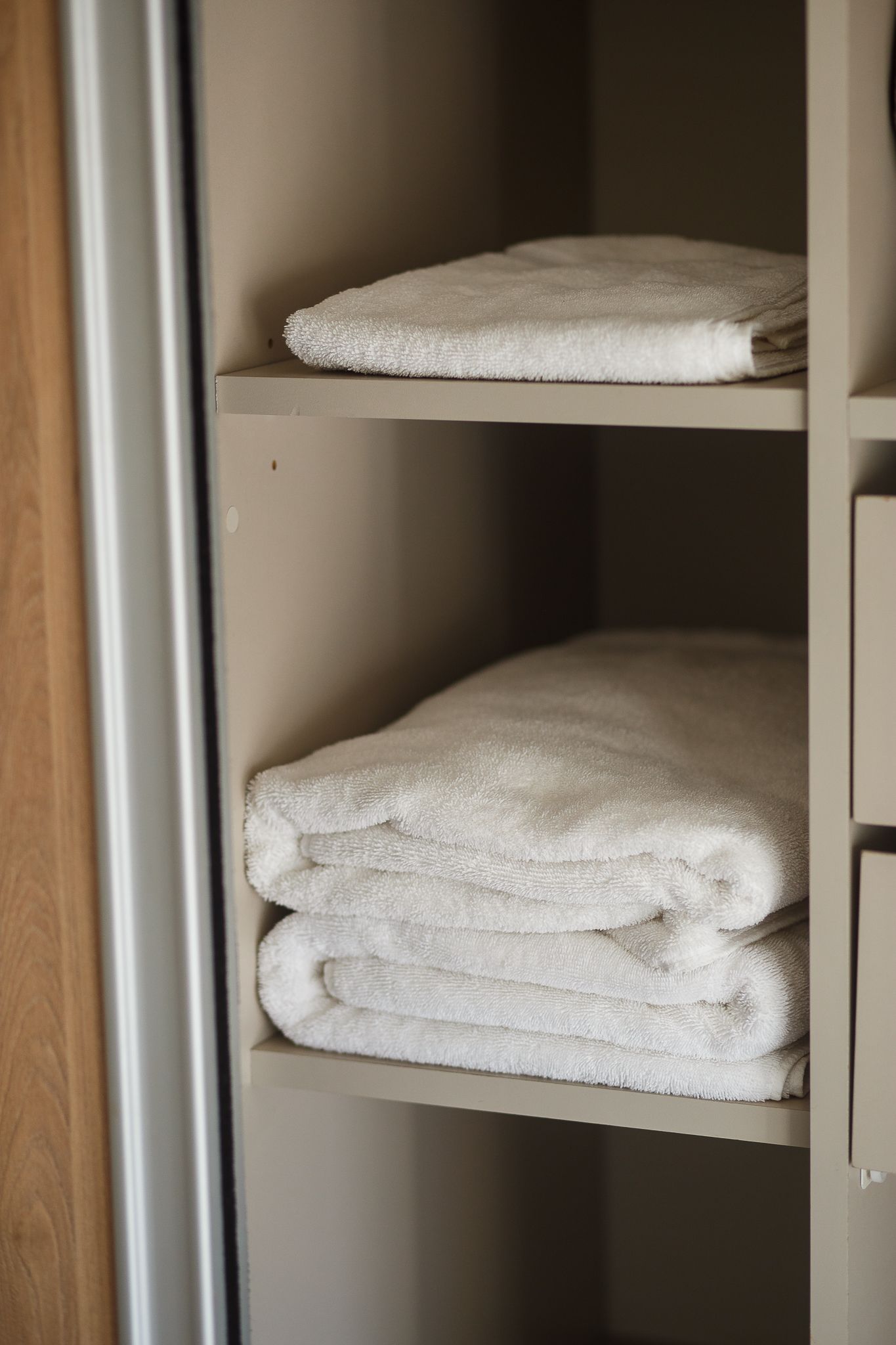 White folded towels stacked on shelves in a closet.