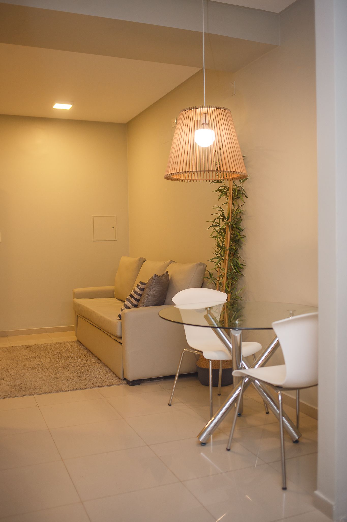 Cozy living space with a sofa, glass table with chairs, and a decorative hanging light.
