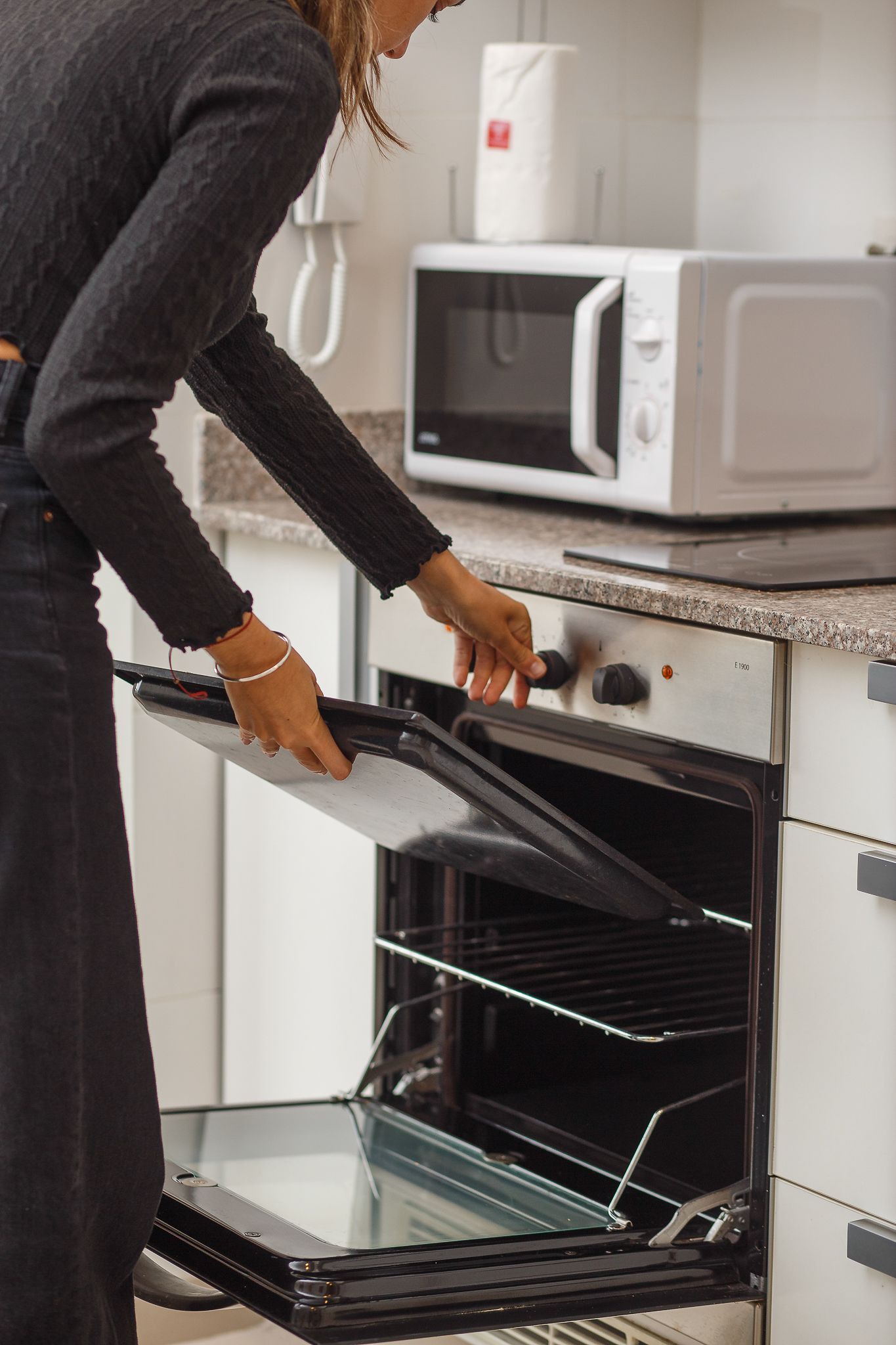 Person opening oven in kitchen, preparing to place or remove something from the interior.